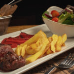 Filete de picanha, patatas fritas, pimientos asados y cuenco de ensalada